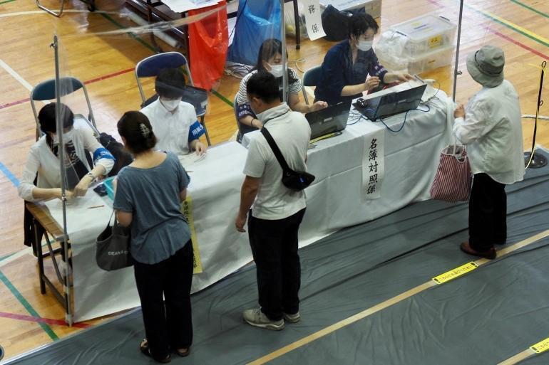2022年7月10日，在日本东京的一个投票站，选民们正在领取选票